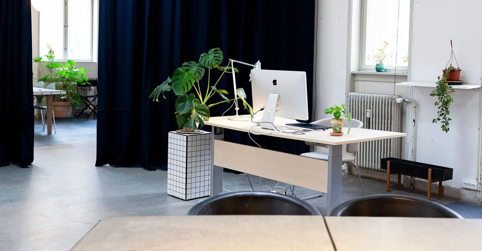 En arbejdsplads med skærm og planter, med forhænget i baggrunden.